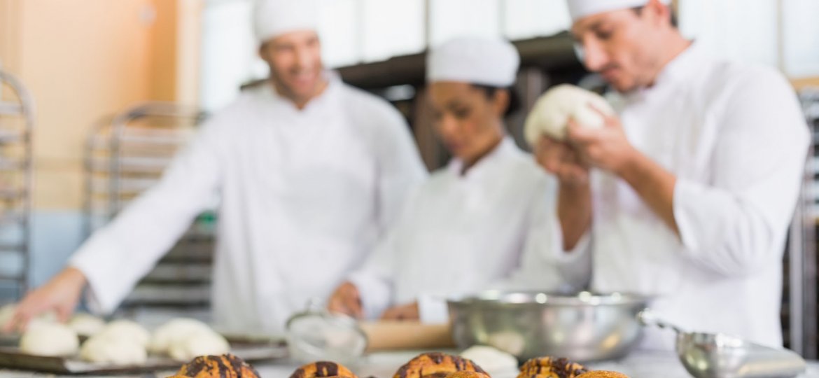 Team of bakers working at counter in the kitchen of the bakery